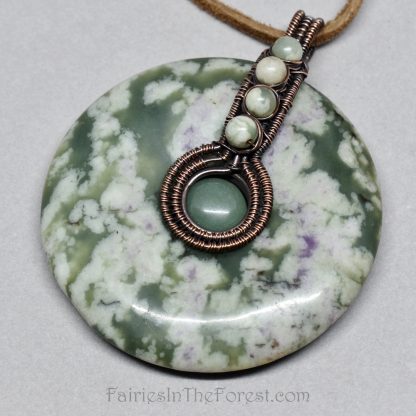 Copper wire wrapped Peace Jade donut pendant on a brown leather necklace.